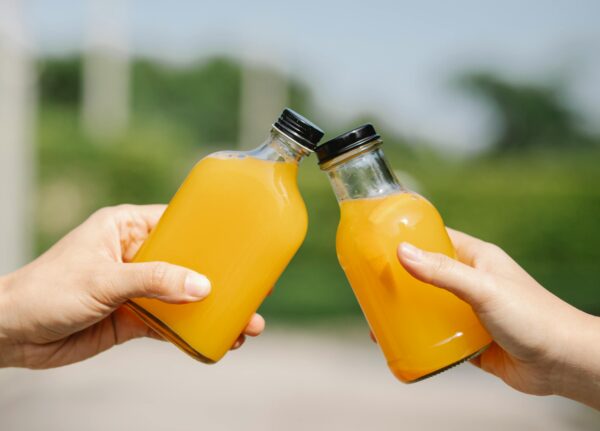 Crop person with bottles of orange juice